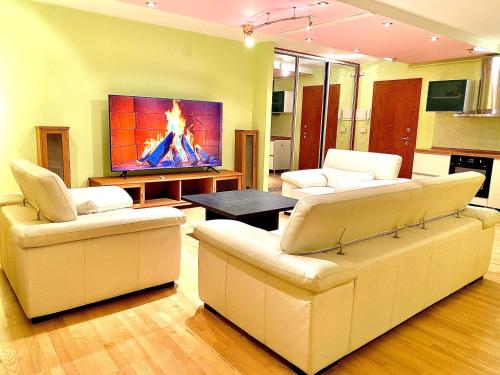 a living room with two white couches and a tv at Sea Aprtment in Klaipėda