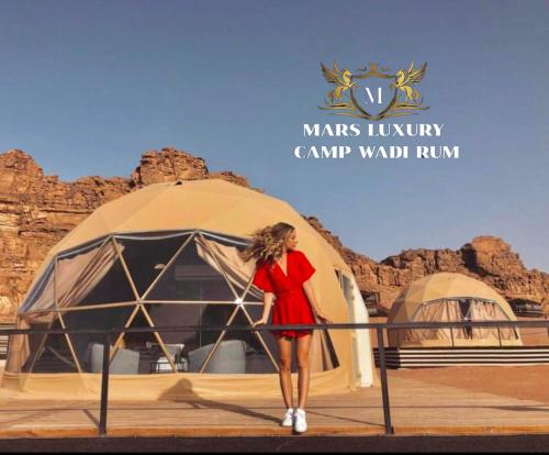a woman in a red dress standing in front of a tent at MARS lUXURY CAMP WADI RUM in Wadi Rum