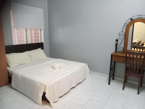 a bedroom with a bed with a chair and a mirror at Ria Homestay & kolam in Alor Setar