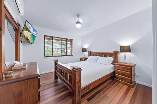 a bedroom with a bed and a desk and a window at Day Dreaming - Mazlin House in Airlie Beach