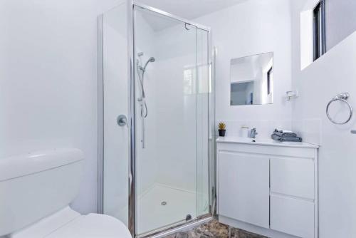 a white bathroom with a shower and a toilet at Day Dreaming - Mazlin House in Airlie Beach