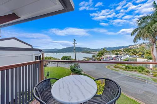 a balcony with a table and chairs and a view of the water at Day Dreaming - Mazlin House in Airlie Beach