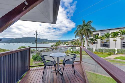 a balcony with a table and chairs and a view of the water at Day Dreaming - Mazlin House in Airlie Beach