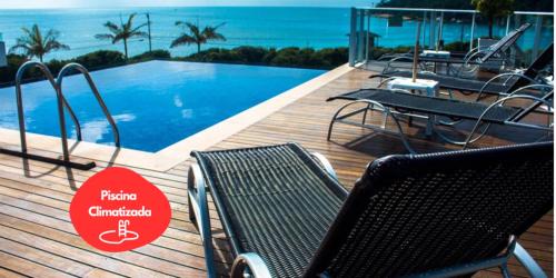 a deck with chairs and a swimming pool with the ocean at Reserva Praia Hotel in Balneário Camboriú