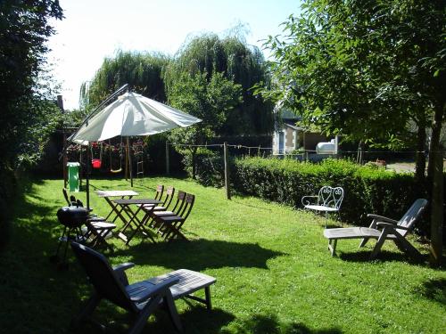 a group of chairs and tables and an umbrella in the grass at Gîte de la Chapelle in Trédarzec