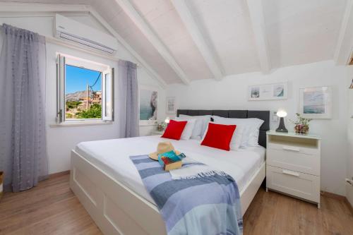 a bedroom with a large white bed with red pillows at Seaside house for families with children Cavtat, Dubrovnik - 22828 in Cavtat