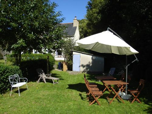 a table and chairs and an umbrella in a yard at Gîte de la Chapelle in Trédarzec