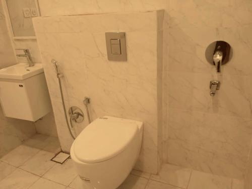 a white bathroom with a toilet and a sink at بيتي بلس للغرف الفندقية- مدخل مستقل in Riyadh Al Khabra
