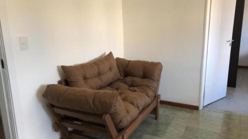 un sofá marrón sentado en la esquina de una habitación en Cómodo Departamento Hogareño en San Carlos de Bariloche