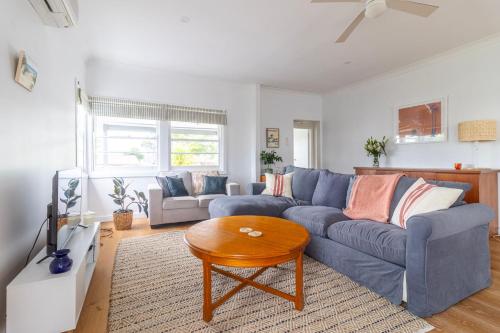a living room with a blue couch and a table at Sussex Beach House in Sussex inlet