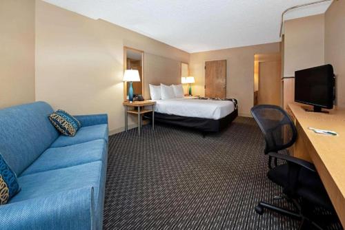 a hotel room with a bed and a couch at La Quinta by Wyndham West Palm Beach Airport in West Palm Beach