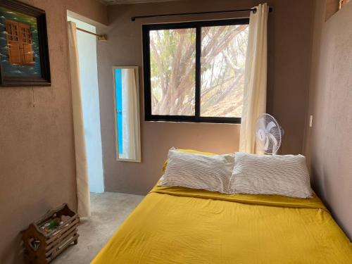 1 dormitorio con cama amarilla y ventana en Casa Tortolita, en Mazunte