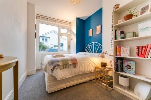 a bedroom with blue walls and a bed and a window at Charming 2 bed Flat with Secluded Garden in Brighton & Hove