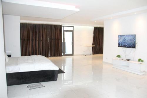 a bedroom with a bed and a flat screen tv at Banner Vacation Home & Swimming Pool in Prampram