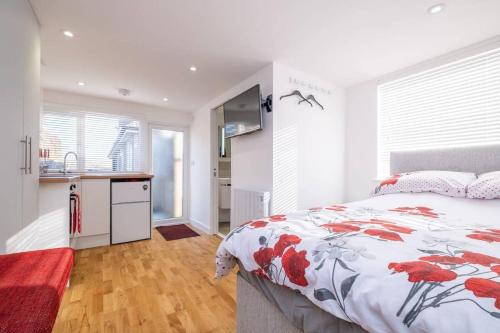 a bedroom with a bed with a red and white comforter at Brand new studio apartment with parking in Brighton & Hove