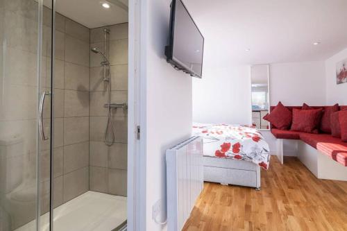 a bathroom with a shower and a television on a wall at Brand new studio apartment with parking in Brighton & Hove