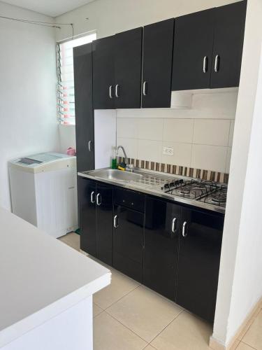 a kitchen with black cabinets and a stove at Lindo Apto con Aire Acond de 3 habitaciones in Valledupar