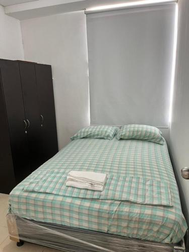 a bedroom with a bed with a green and white blanket at Lindo Apto con Aire Acond de 3 habitaciones in Valledupar