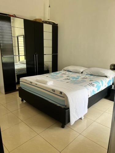 a bedroom with a bed and a refrigerator in it at Lindo Apto con Aire Acond de 3 habitaciones in Valledupar
