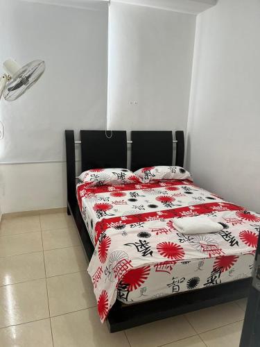 a bedroom with a bed with a red and white comforter at Lindo Apto con Aire Acond de 3 habitaciones in Valledupar