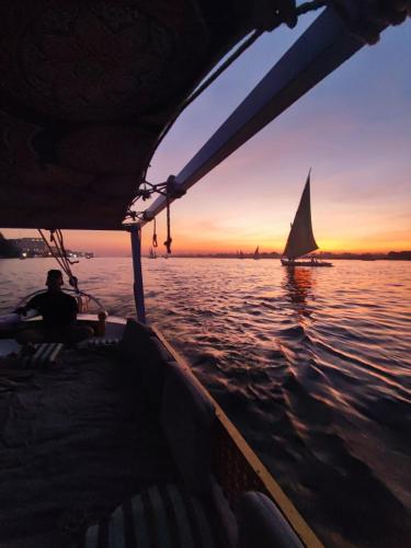 a man on a boat in the water with a sailboat at Felucca.sailing.Boat in Luxor