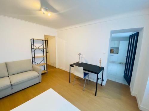 a living room with a couch and a desk at Appartement Confortable - Trignac Centre Ville in Trignac