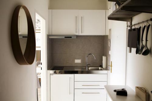 cocina con armarios blancos, lavabo y espejo en Central Rooftop Apartment with Balcony en Viena