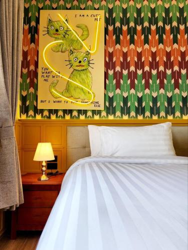 a bedroom with a bed and a poster of two cats at Senglao Boutique Hotel Luang Prabang in Luang Prabang