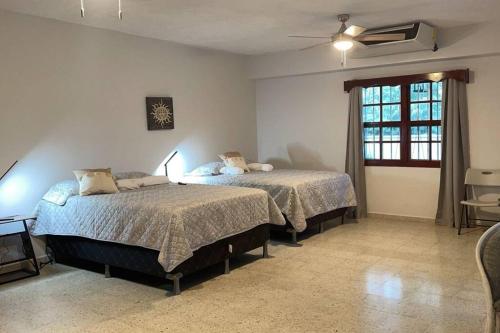 1 dormitorio con 2 camas y ventana en Casa Luna Azul, en La Ceiba