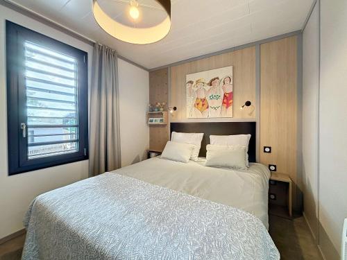 une chambre avec un lit blanc et une fenêtre dans l'établissement Chalet de standing pour 4 pers., piscine couverte et chauffée, à deux pas de la plage, Wi-Fi gratuit - FR-1-361-515, à Jullouville