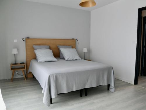a bedroom with a white bed with a wooden headboard at Maison Anglet, 4 pièces, 6 personnes - FR-1-239-758 in Anglet