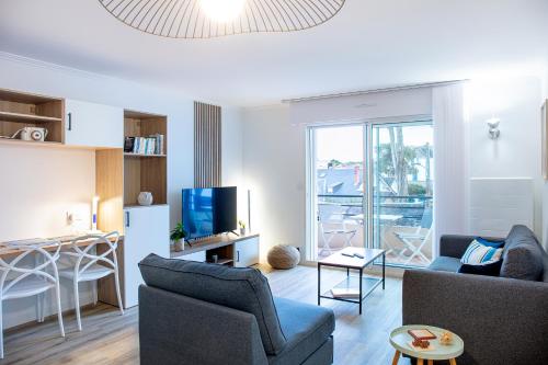 un salon avec un canapé, des chaises et une télévision dans l'établissement Plage à pied - Parking - T2 spacieux et balcon, à La Baule