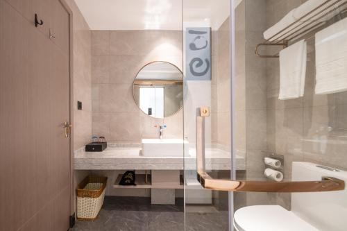 uma casa de banho com um lavatório, um WC e um espelho. em Poltton International Hotel - Huizhou University of economics em Huizhou