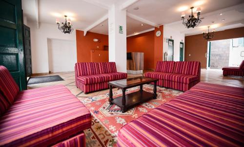 a waiting room with red chairs and a table at Hotel Raymi in Cusco