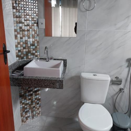 a bathroom with a white toilet and a sink at Vila do Vento in Lavras Novas