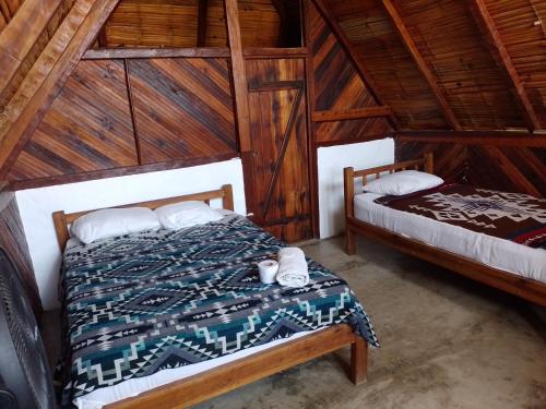 a bedroom with two beds in a wooden cabin at Hotel Palma Coco in Ayampe