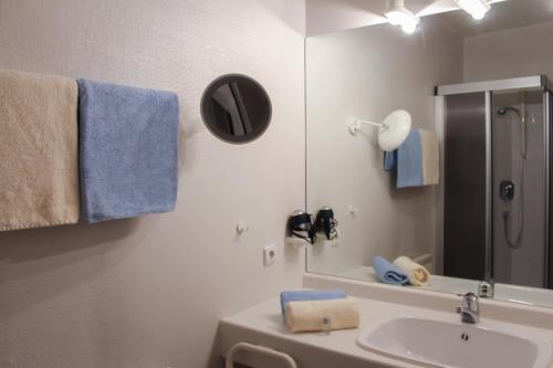 y baño con lavabo, espejo y toallas azules. en Hotel Post, en Rosbach vor der Höhe