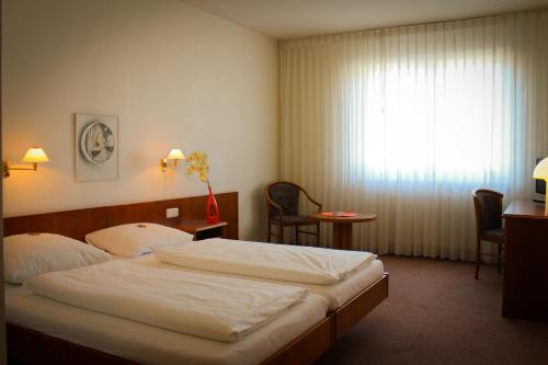 una camera d'albergo con letto e finestra di Hotel Post a Rosbach vor der Höhe