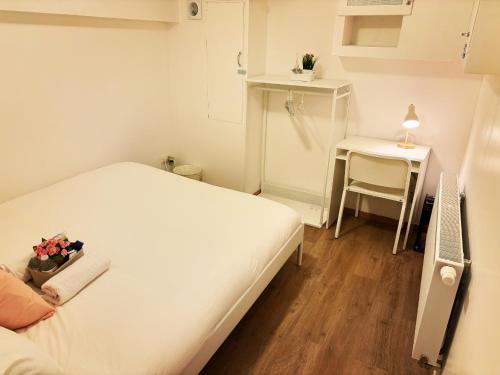 a small white bedroom with a bed and a table at Benny's Rooms Brussels City Centre in Brussels