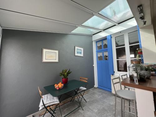 une cuisine avec une table et des chaises ainsi qu'une porte bleue dans l'établissement Maison rénovée près de la plage avec jardinet et wifi - FR-1-485-4, à Les Sables-dʼOlonne