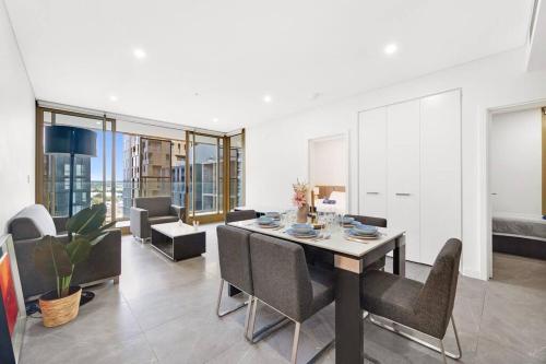 a dining room and living room with a table and chairs at SOP 99 Modern 3 Bedroom with Pool & Free Parking in Sydney