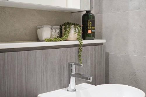 - un lavabo dans la salle de bains avec une bouteille de vin sur une étagère dans l'établissement Sydney Olympic Park Modern 3 Bedroom with Pool & Free Parking, à Sydney