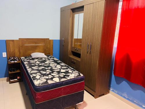 a bedroom with a bed and a wooden cabinet at Suíte privativa in Parintins