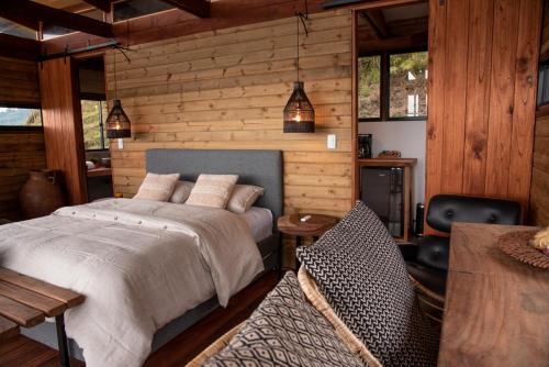 1 dormitorio con 1 cama y pared de madera en Owl's Watch Nature Retreat, en Manizales
