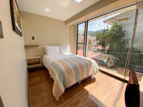 a bedroom with a bed and a large window at Huallata Hotel Boutique in Huaraz