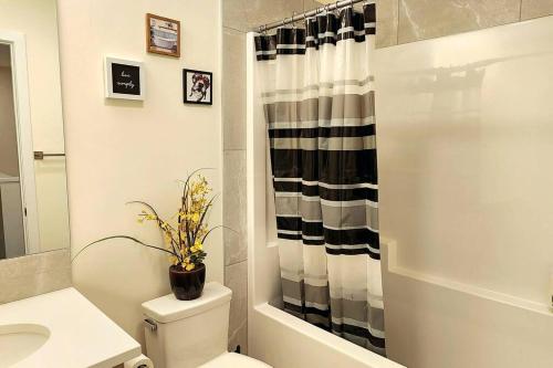 a bathroom with a toilet and a black and white shower curtain at Comfortable entire townhouse in downtown Edmonton. in Edmonton