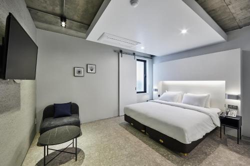 a bedroom with a large bed and a chair at Hotel Intro in Busan