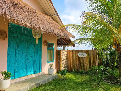 a house with a blue door and a fence at Janur Bungalow in Borobudur