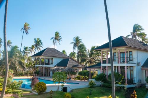 un complejo con piscina y palmeras en Zawadi Beach Villas, en Matemwe