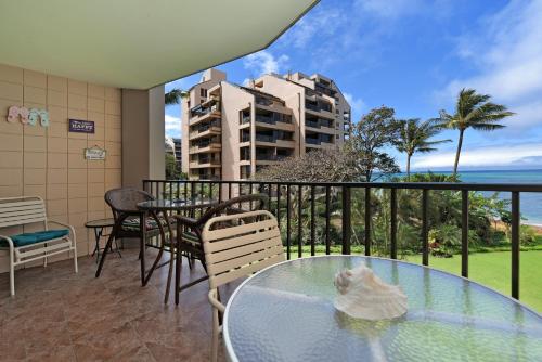 a balcony with a glass table and chairs and the ocean at Valley Isle 302 in Kahana